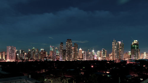 Illuminated buildings in city against sky at night