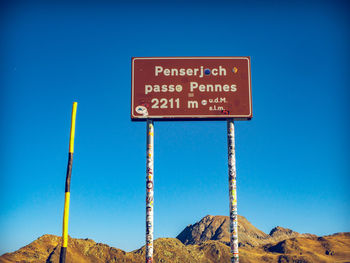 Low angle view of information sign against clear blue sky