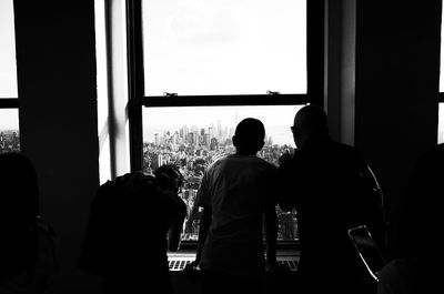 Rear view of silhouette people standing against window