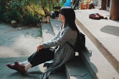 Young woman sitting on retaining wall