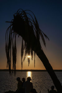 Silhouette palm tree at beach against sky during sunset