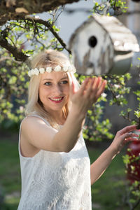 Beautiful woman touching birdhouse at backyard