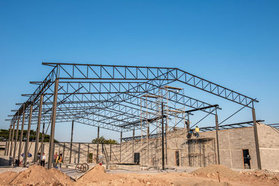 Low angle view of construction site against clear blue sky