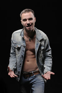 Portrait of male fashion model standing against black background