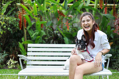 Portrait of woman with dog sitting on bench