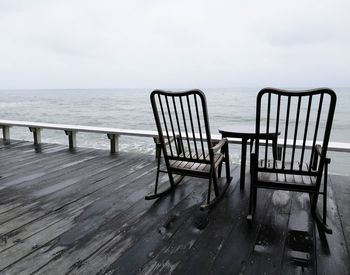 Empty chair on sea against sky