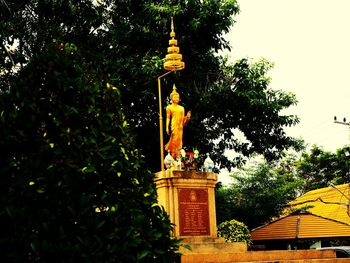 Low angle view of statue by building against sky