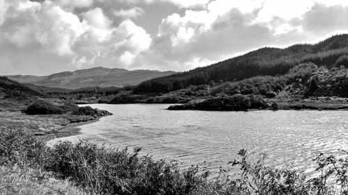 Scenic view of river by mountains against sky