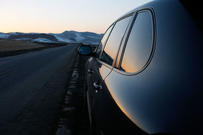 Car moving on road against clear sky during sunset