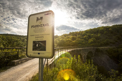 Information sign by road against sky