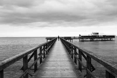 Pier on sea against cloudy sky