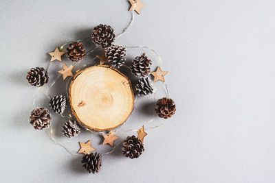 Christmas background, garland and pine cones around a cut tree trunk on gray