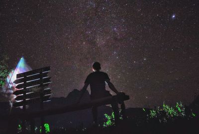 Rear view of man standing against sky at night