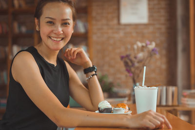 Young women looking at camera with beautiful smile and she has dessert on table , relaxation concept