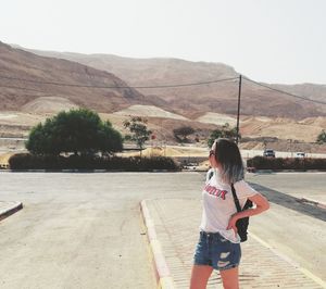 Rear view of woman standing on road against sky