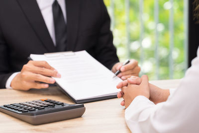 Midsection of man holding hands on table