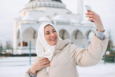 Portrait of smiling woman photographing with mobile phone