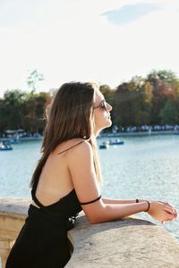 Side view of young woman wearing sunglasses against sky