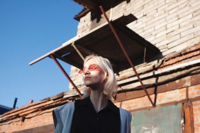 Low angle portrait of young woman against building