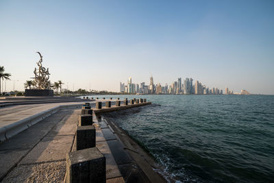 View of doha city by sea against clear sky