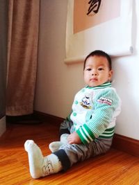 Portrait of cute girl sitting on hardwood floor at home