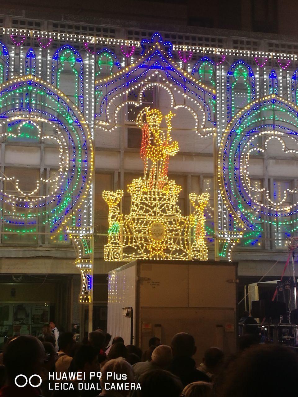 GROUP OF PEOPLE IN FRONT OF ILLUMINATED BUILDING