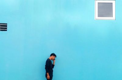 Full length of man standing against building against clear blue sky