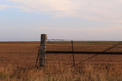 Fence on farm against cloudy sky