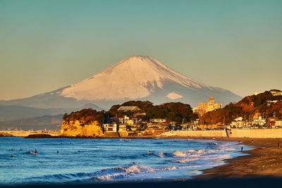 Scenic view of sea against clear sky and snow covered mountain