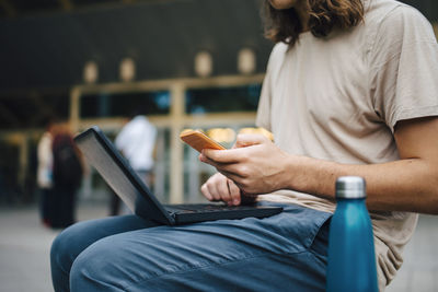 Midsection of man using mobile phone