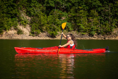 Woman in boat on lake against trees