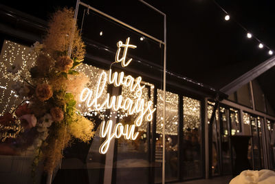 Low angle view of illuminated lighting equipment hanging at night