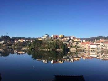 Reflection of buildings in city against clear blue sky