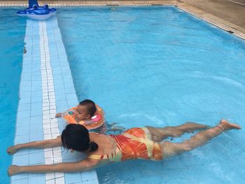 High angle view of mother with daughter swimming in pool