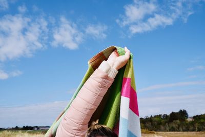 Close-up of hand holding towel against sky