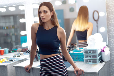 Young woman standing against mirror