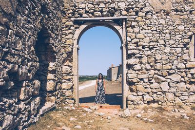 Woman standing at archway on sunny day