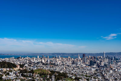 Aerial view of city buildings against blue sky