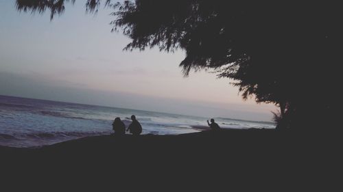 Silhouette people on beach against sky during sunset