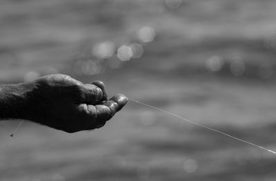 Cropped hand of man holding fishing rod