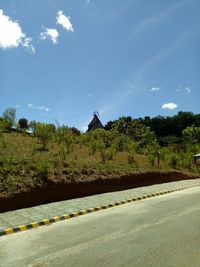 Road by trees in city against sky