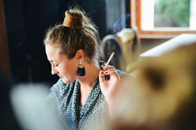 Woman smoking cigarette at home