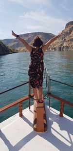 Rear view of woman standing by sea against sky