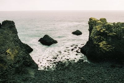 Rocks on sea shore against sky