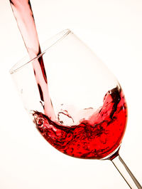 Close-up of red wine glass against white background