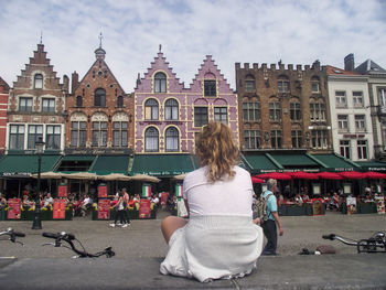 Rear view of woman on street against buildings in city