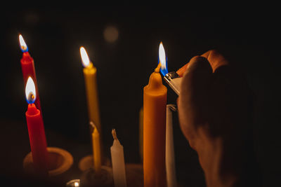 Close-up of hand holding lit candles in darkroom