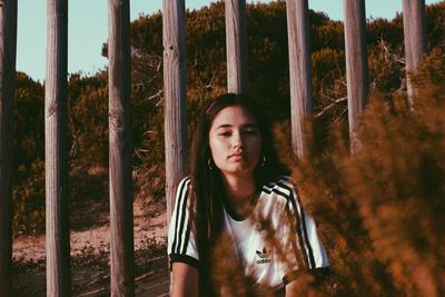 Portrait of teenage girl standing by tree trunk