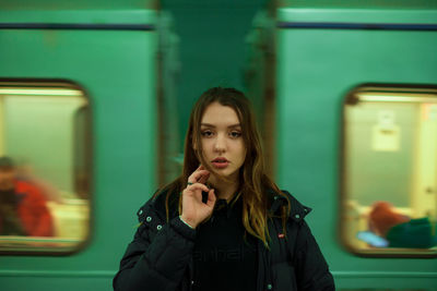 Portrait of beautiful woman standing against train