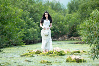 Woman standing by plants against trees